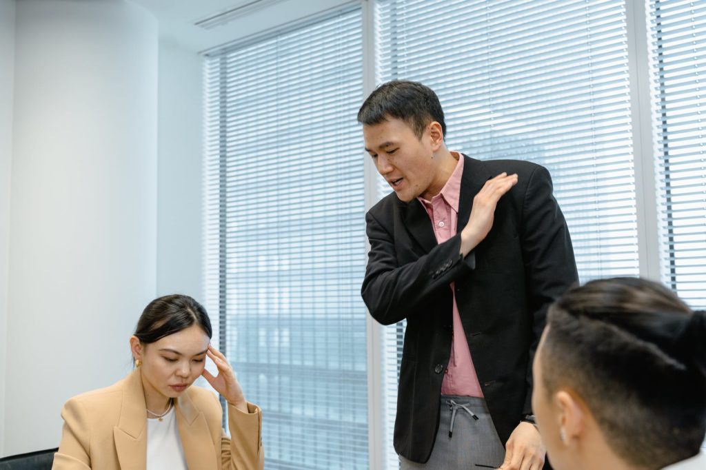 man standing and talking seriously to employees