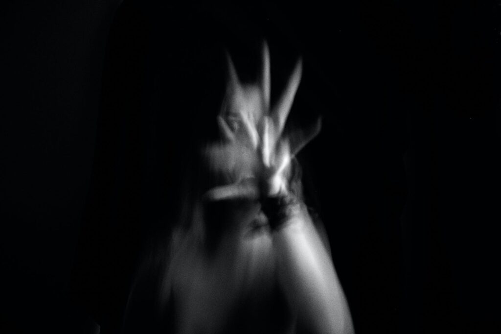 blurred motion of woman with her hand up and reaching towards the camera