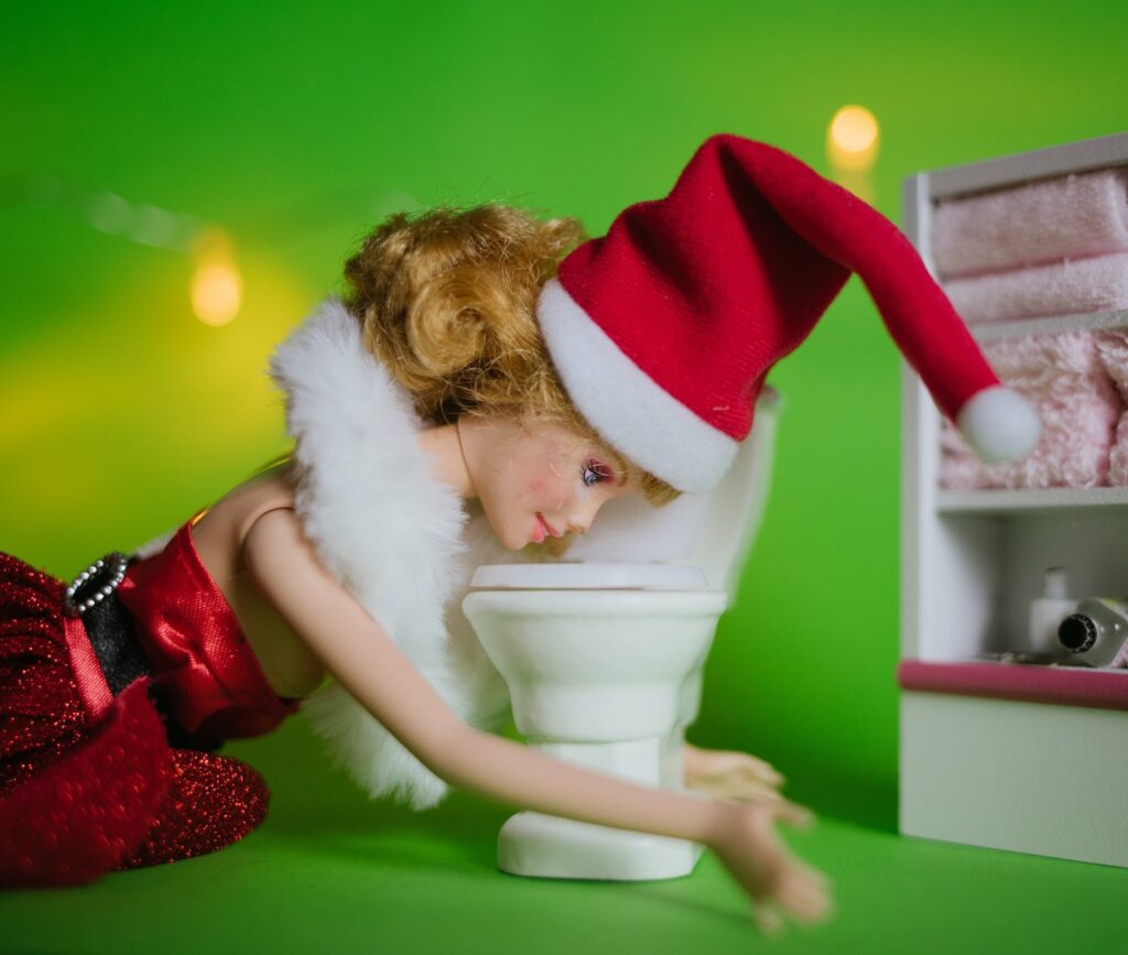 a doll wearing santa hat throwing up in a toilet bowl