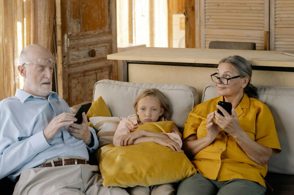 a girl sitting on a couch with her grandparents