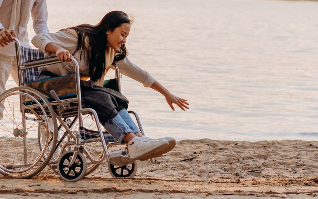 woman reaching for the sand while sitting on the wheelchair